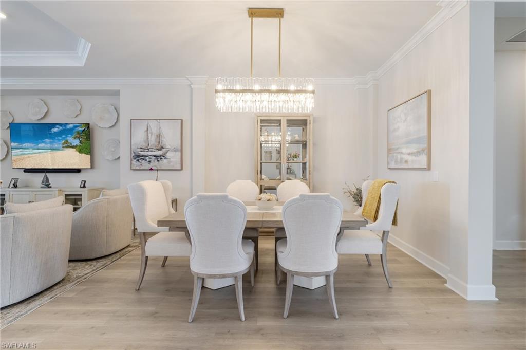 Dining area with ornamental molding, light wood-style flooring, and a chandelier