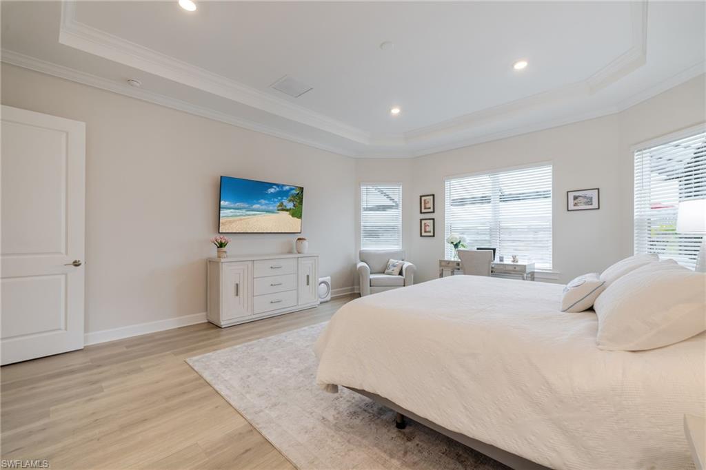 Bedroom featuring light wood-style floors, a raised ceiling, recessed lighting, and crown molding