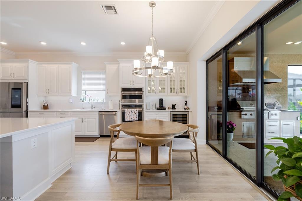 Dining space featuring light wood-style floors, plenty of natural light, ornamental molding, and hanging lights