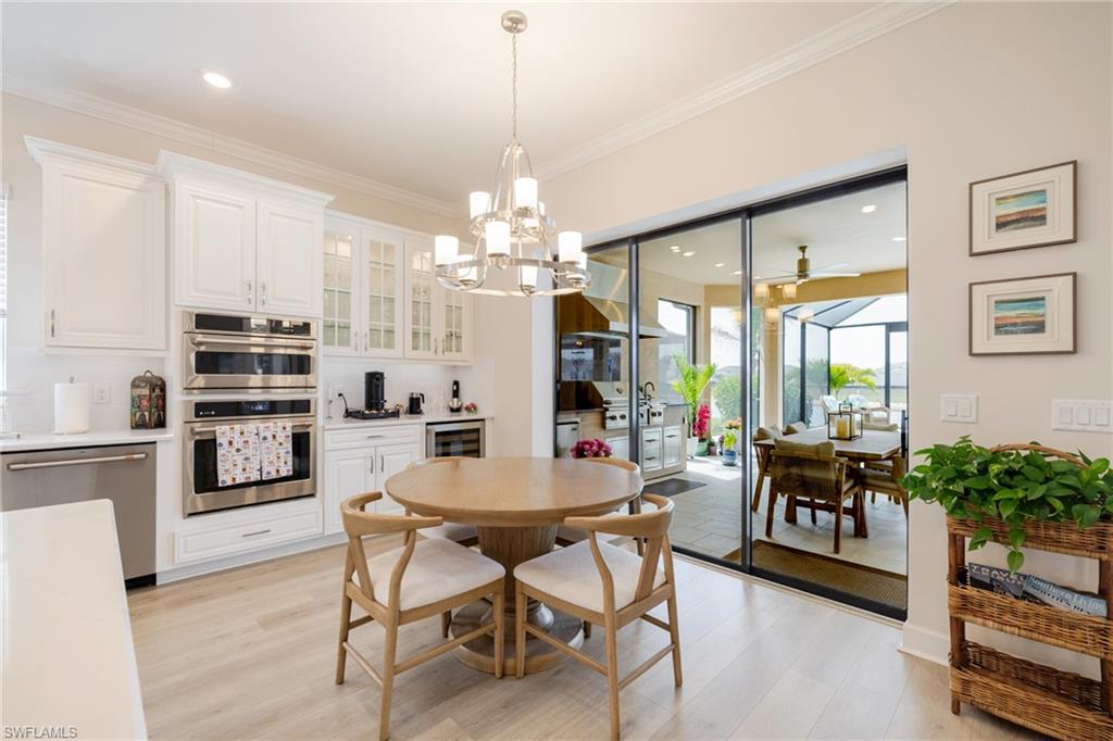 Dining space with a chandelier, light wood-style floors, ceiling fan, crown molding, and beverage cooler