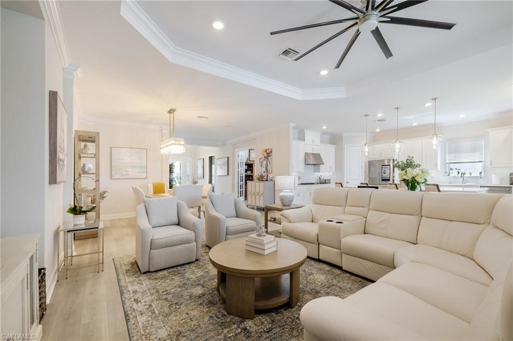 Living area featuring a ceiling fan, light wood-style floors, recessed lighting, crown molding, and a tray ceiling