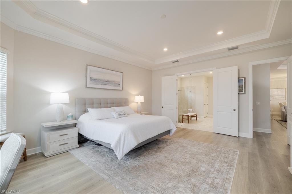 Bedroom featuring light wood-style floors, crown molding, a raised ceiling, recessed lighting, and multiple windows