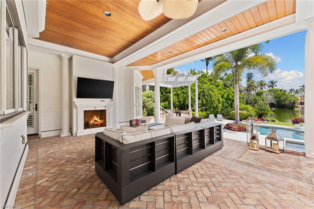 View of patio / terrace featuring a pergola, an outdoor living space with a fireplace, a ceiling fan, a baseboard radiator, and a fenced in pool