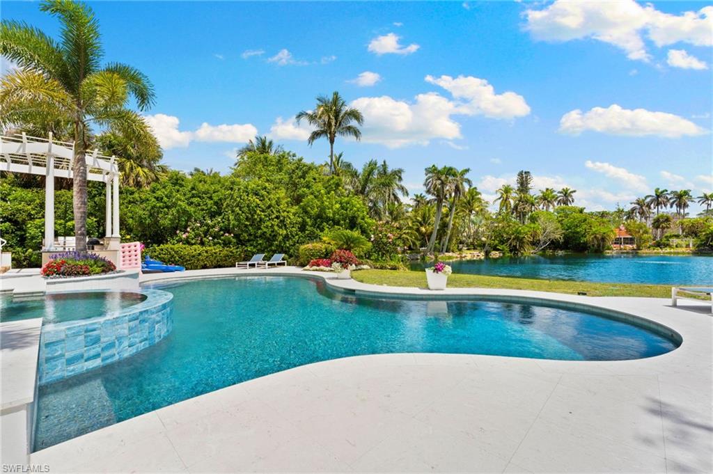 View of swimming pool featuring a pergola, a patio area, a pool with connected hot tub, and a water view
