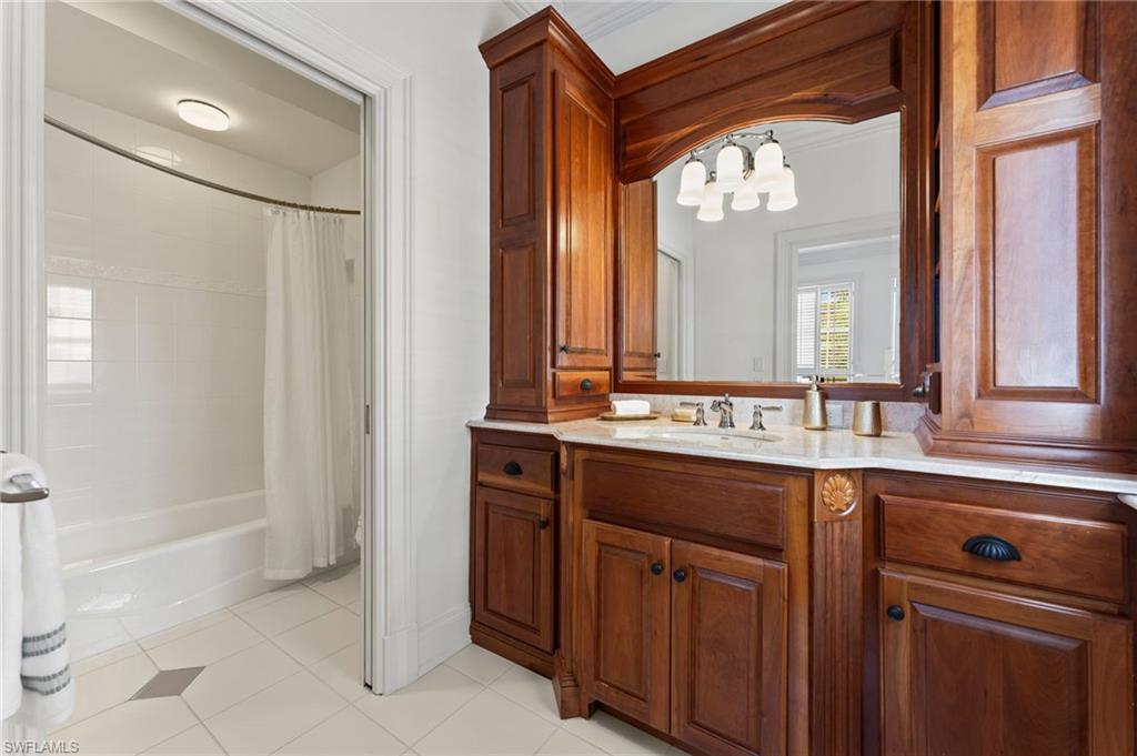 Bathroom with a chandelier, vanity, tile patterned flooring, and shower / bath combo with shower curtain