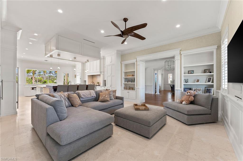 Living room with recessed lighting, built in features, ornamental molding, and a ceiling fan