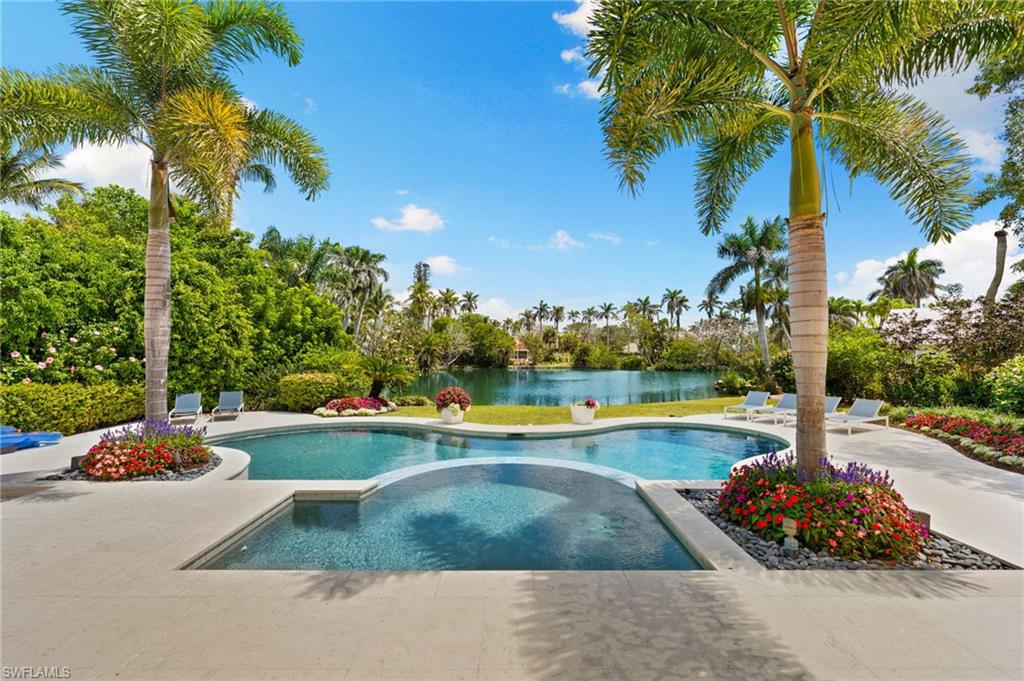 Outdoor pool with a patio area, an in ground hot tub, and a water view