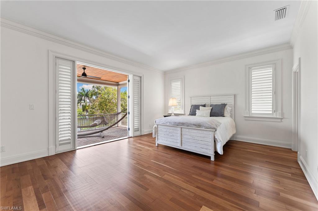 Bedroom with visible vents, baseboards, ornamental molding, wood finished floors, and access to outside