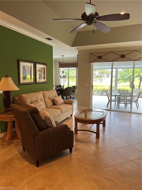 Open-concept living area featuring warm wood-finish flooring, a ceiling fan with bronze finish, and abundant natural light from expansive glass sliding doors