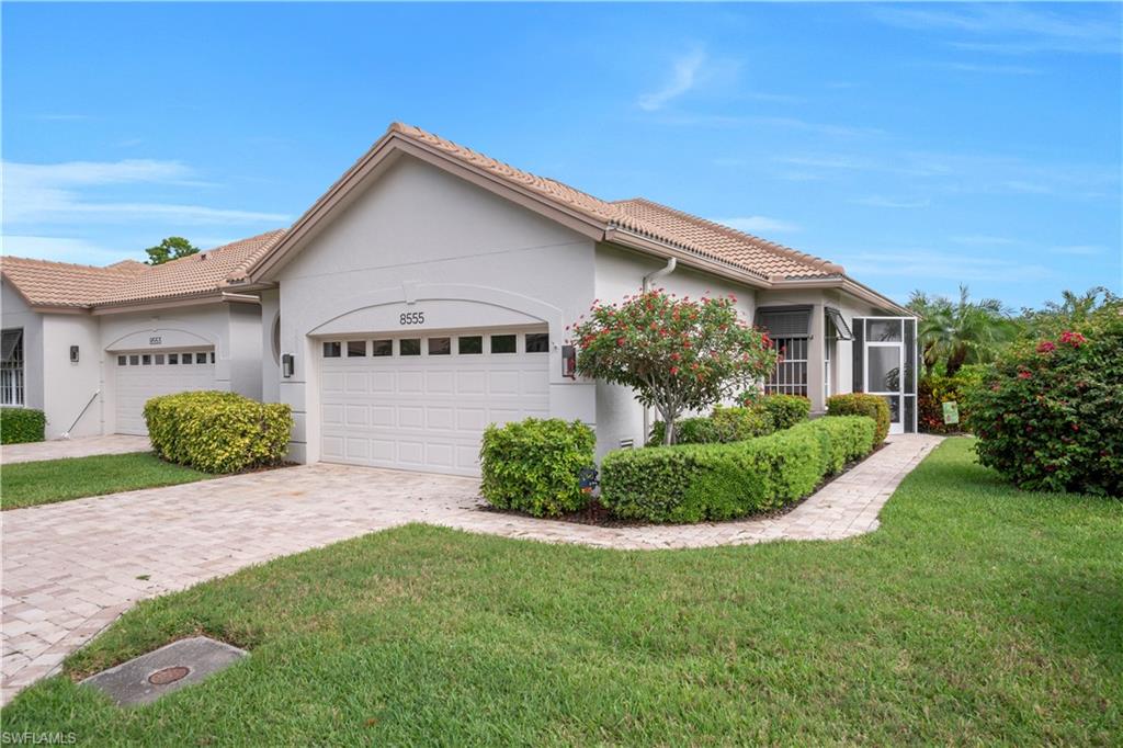 Ranch-style home with stucco siding, an attached garage, decorative driveway, a front yard, and a tile roof