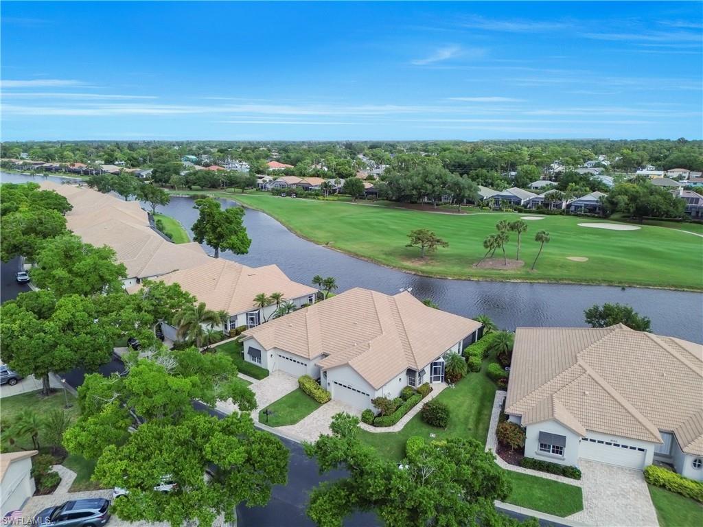 Aerial perspective of suburban area featuring a golf course and a nearby body of water