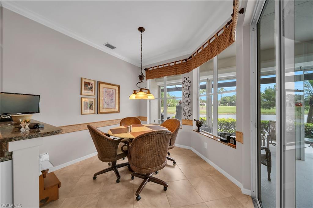Dining space with crown molding, a water view, a desk, and light tile patterned flooring
