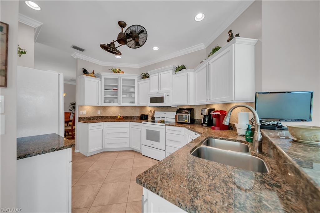 Kitchen with white cabinetry, glass fronted cabinets, white appliances, ornamental molding, and recessed lighting