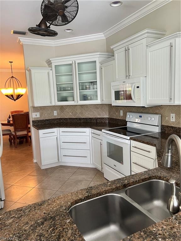 White cabinetry with glass-front accents, solid surface countertops, a mosaic tile backsplash, stainless steel double basin sink, and tile flooring