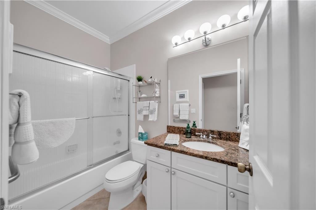 Bathroom with enclosed tub / shower combo, vanity, and ornamental molding