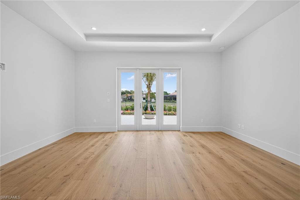 Master bedroom with lots of natural lighting, wood flooring, a tray ceiling, and recessed lighting