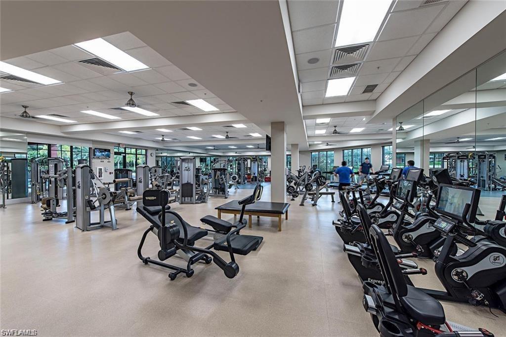 This extensive fitness center features a comprehensive array of exercise equipment, large windows, and mirrored walls
