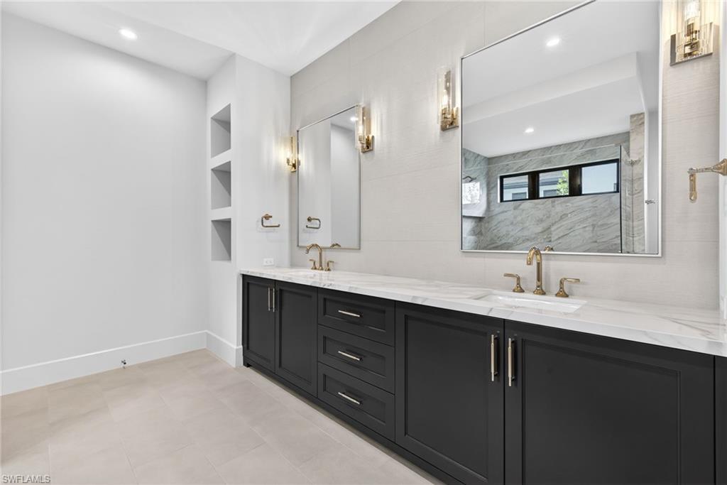 Master bathroom with double vanity, built in features, recessed lighting, and a marble finish shower