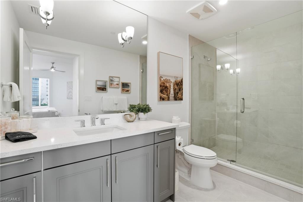 Ensuite bathroom with vanity, a stall shower, a chandelier, a ceiling fan, and light tile patterned flooring - Virtually Edited Image