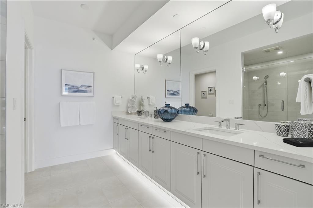 Full bath featuring a stall shower, double vanity, and light tile patterned floors - Virtually Edited Image