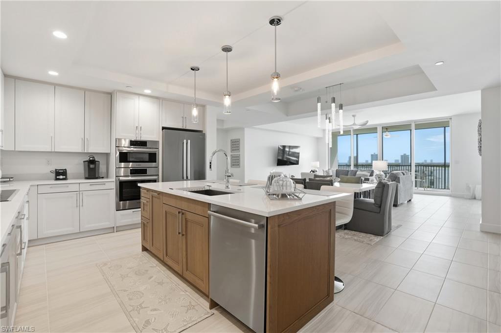 Kitchen featuring a tray ceiling, white cabinets, open floor plan, appliances with stainless steel finishes, and recessed lighting - Virtually Edited Image