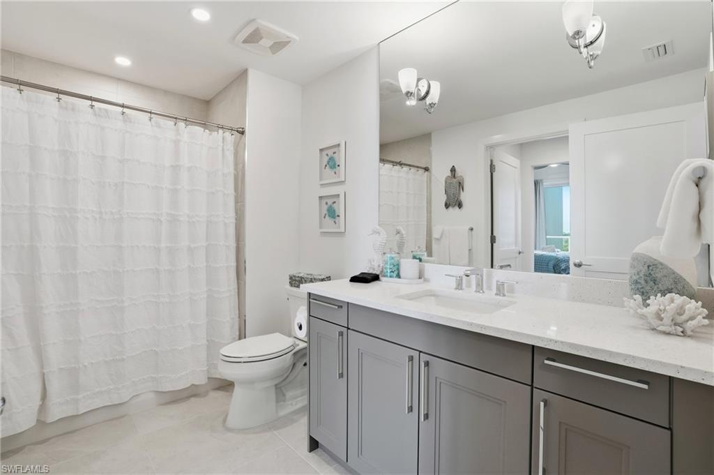 Full bath featuring connected bathroom, vanity, light tile patterned flooring, recessed lighting, and a shower with curtain - Virtually Edited Image