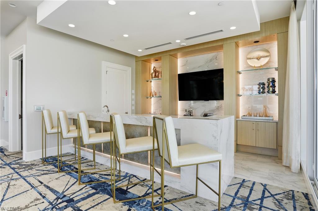 Indoor wet bar in the community center featuring recessed lighting, light marble finish flooring, and light stone counters- Virtually Edited