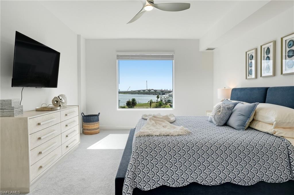 Bedroom featuring light carpet, ceiling fan, and a water view - Virtually Edited Image
