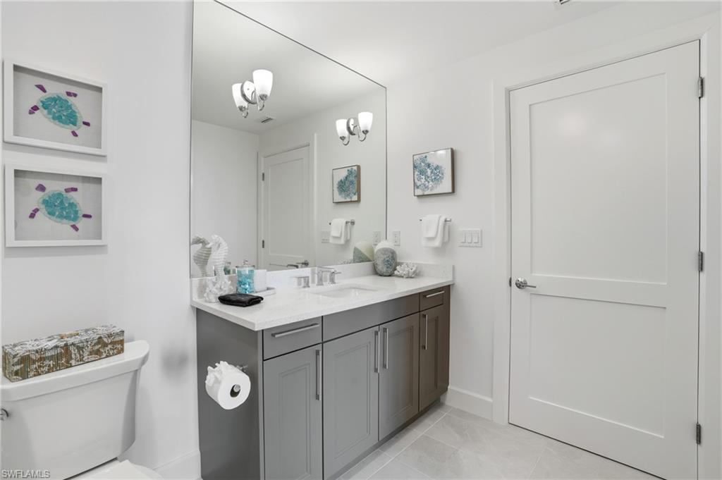 bathroom featuring vanity, light tile patterned floors, and a chandelier - Virtually Edited Image