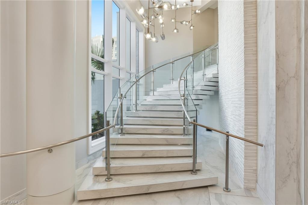 Stairway of Lobby featuring marble finish floors and a chandelier- Virtually Edited