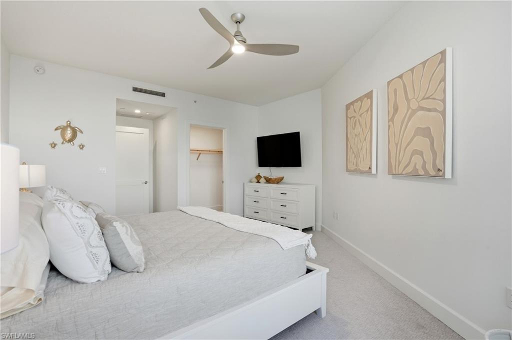 Bedroom featuring light colored carpet, a ceiling fan, and a spacious closet - Virtually Edited Image