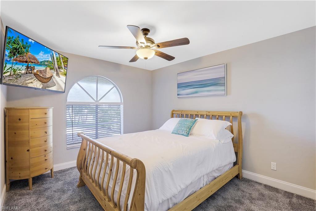Bedroom with a ceiling fan and dark carpet