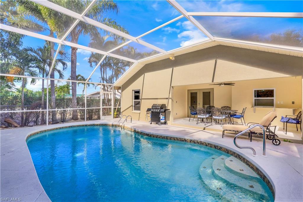 Swimming pool featuring area for grilling, glass enclosure, a sunroom, a patio, and outdoor dining space