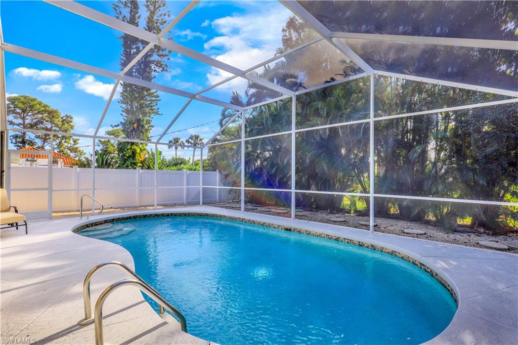 View of pool with a fenced backyard, glass enclosure, a sunroom, and patio surround