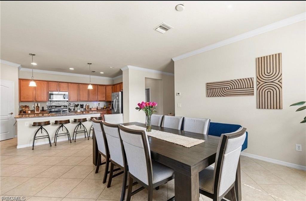 Dining space featuring ornamental molding and light tile patterned floors