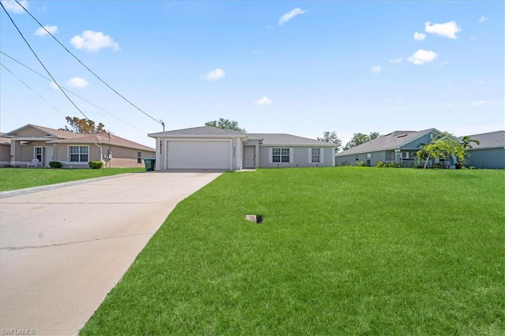 Ranch-style house featuring a front yard, concrete driveway, and an attached garage
