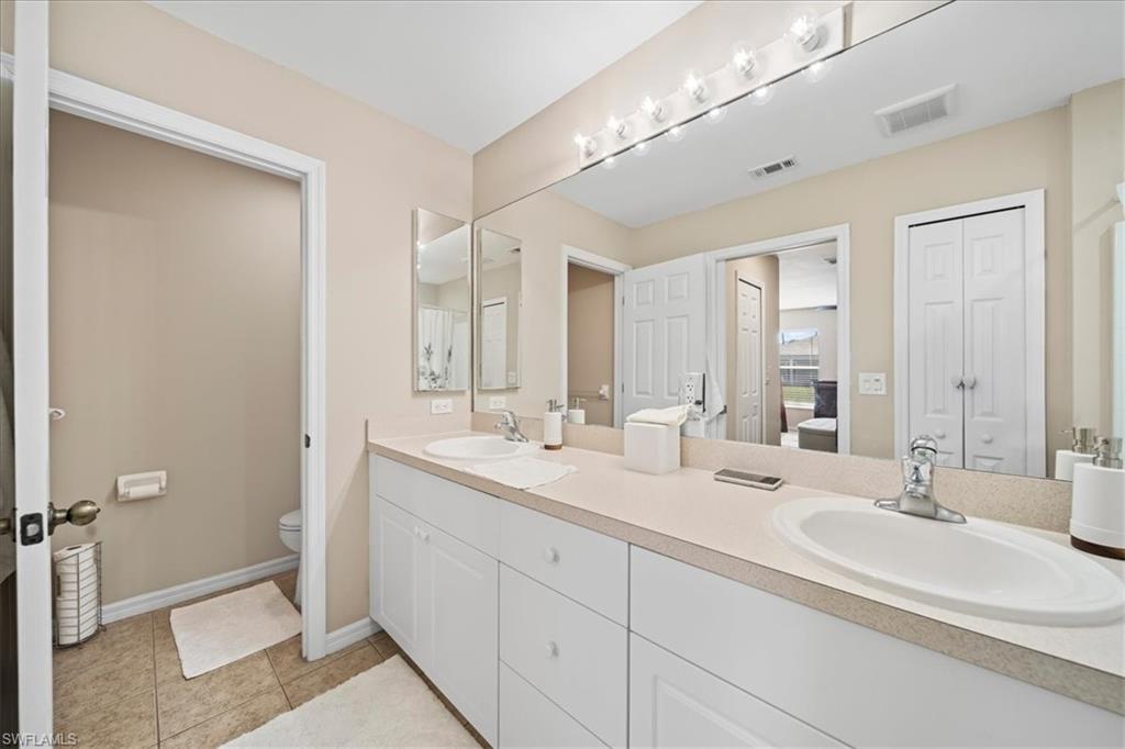 Full bathroom featuring a closet, double vanity, and light tile patterned floors