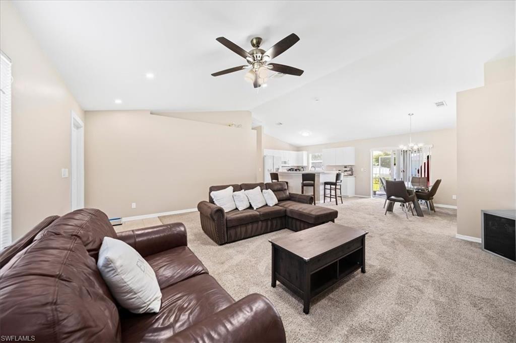 Living area with ceiling fan, carpet flooring, suspended lighting, and lofted ceiling