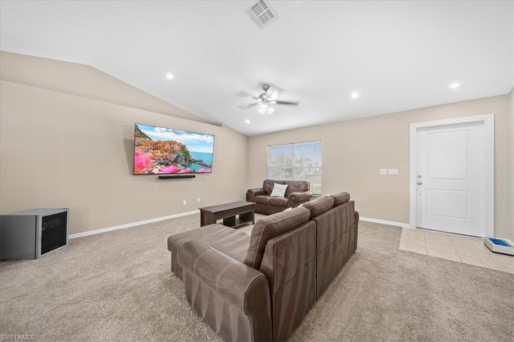 Living area featuring light carpet, a ceiling fan, lofted ceiling, and recessed lighting