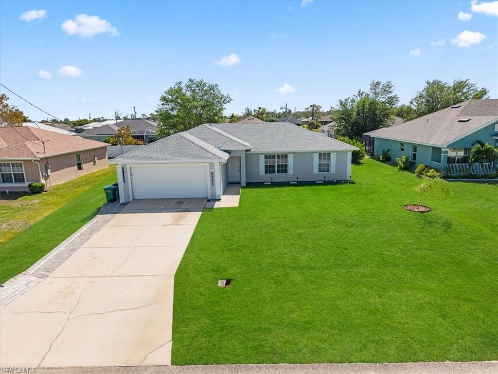 Single story home featuring a front yard, driveway, a residential view, and a garage