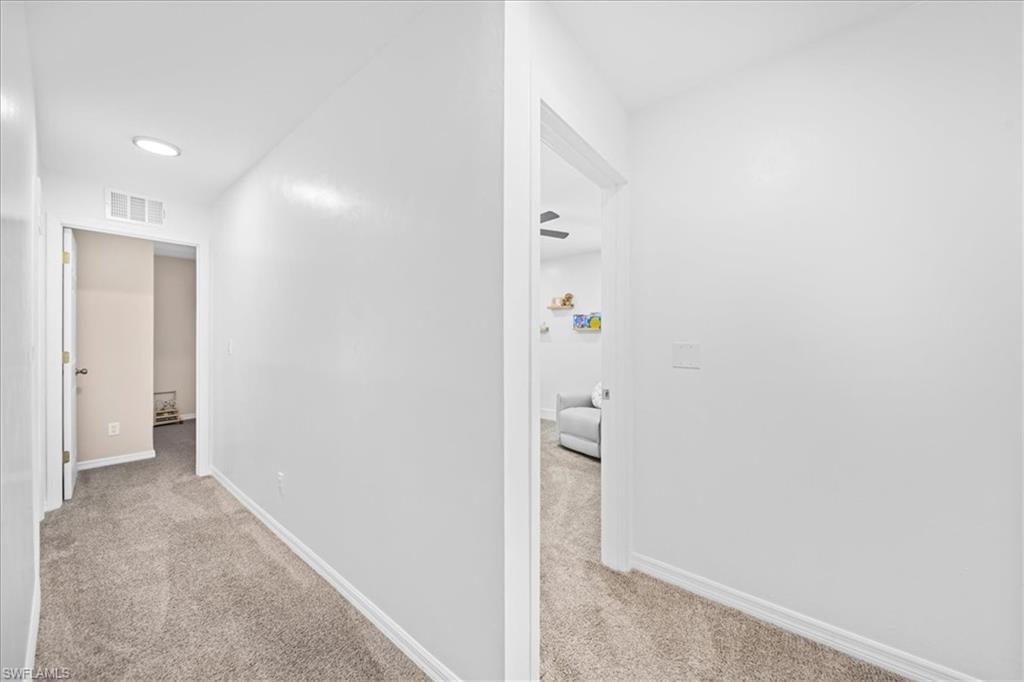 Corridor featuring light carpet