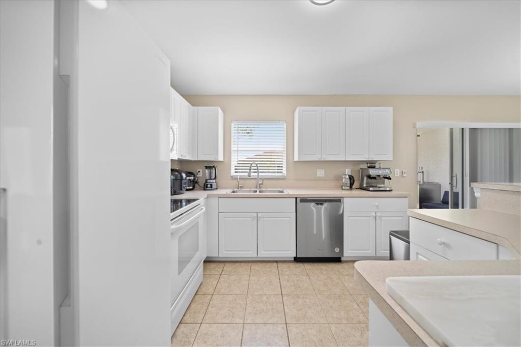 Kitchen featuring white cabinets, light countertops, white range, and stainless steel dishwasher