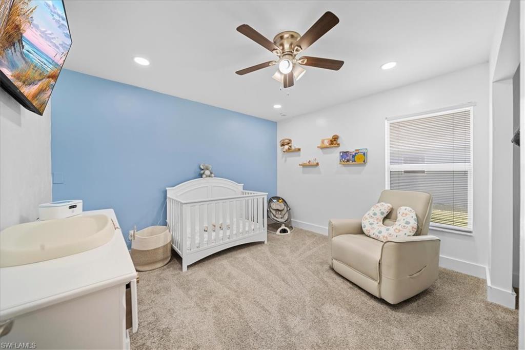 Carpeted bedroom with a crib, a ceiling fan, and recessed lighting