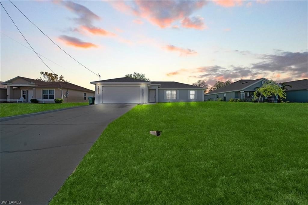 Single story home with a garage, a lawn, and concrete driveway
