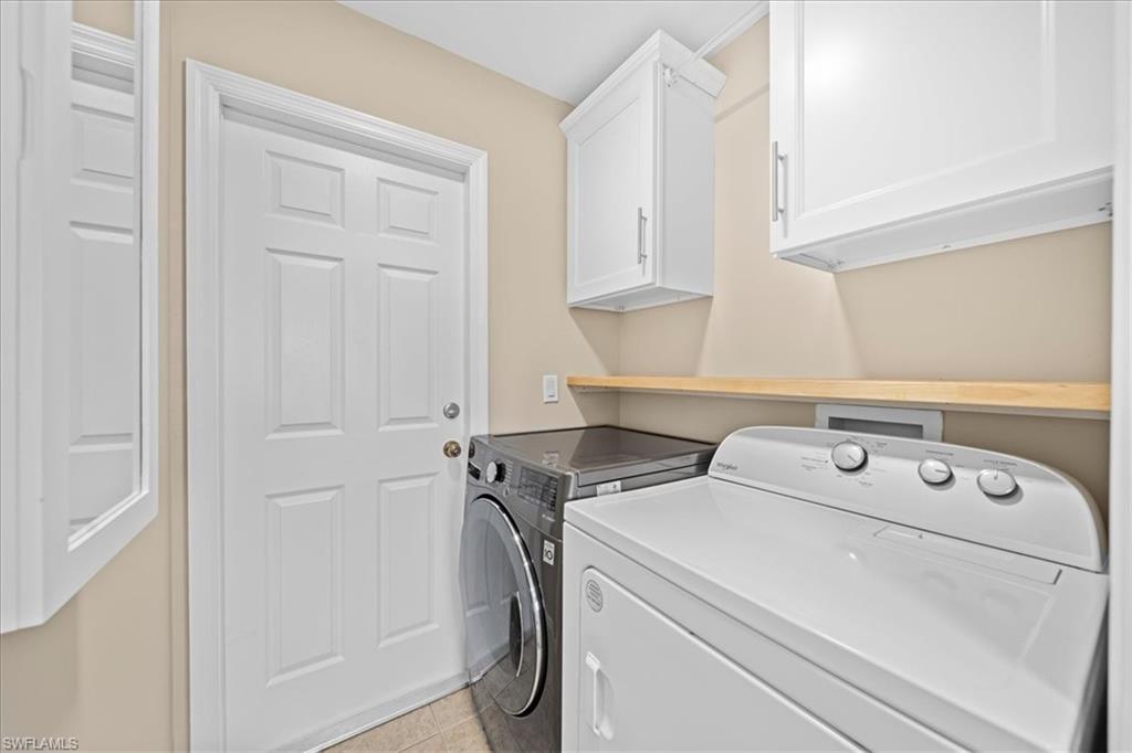 Laundry area featuring cabinet space, washer and dryer, and light tile patterned floors