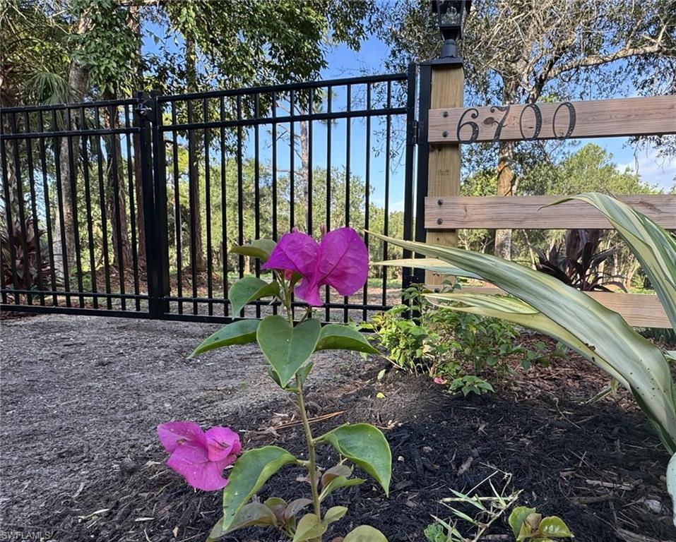 Metal security gate with a wooden address post, featuring a decorative lantern fixture