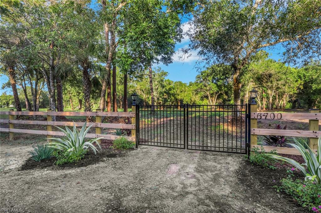 Gated entry with a wood-plank fence and mature landscaping