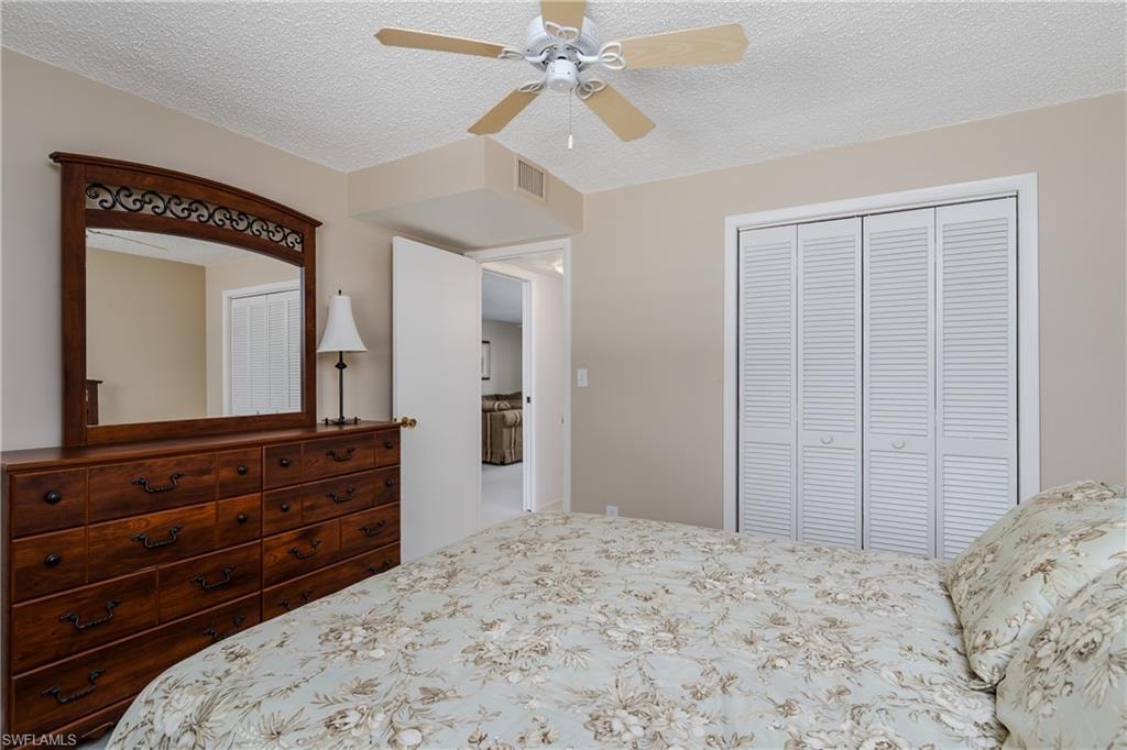 Bedroom with a textured ceiling, a closet, and ceiling fan