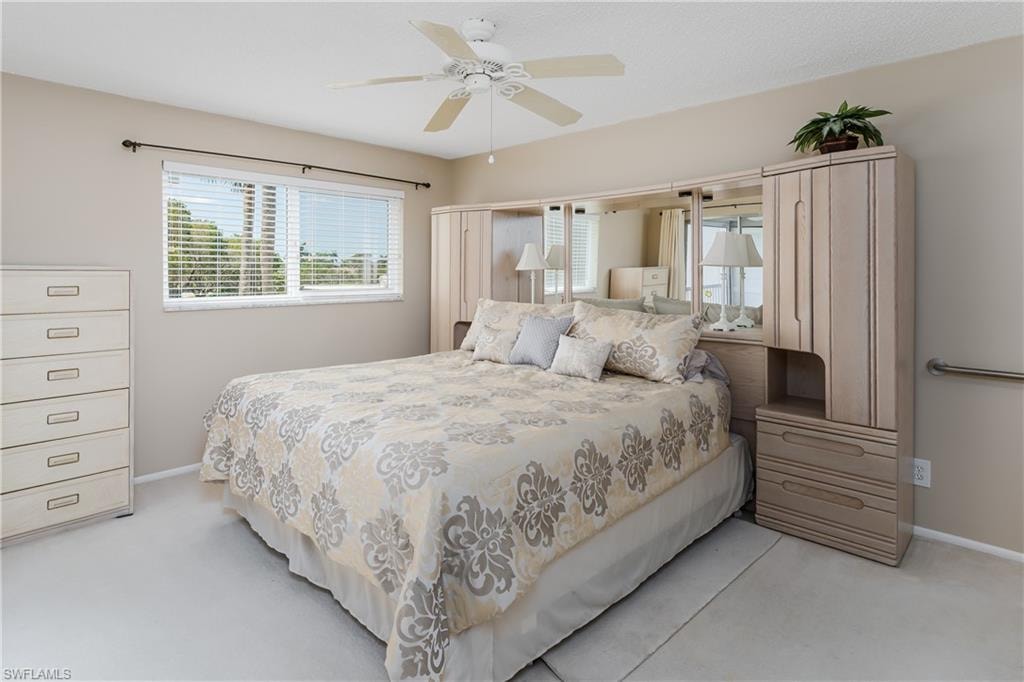 Bedroom with baseboards, light colored carpet, and ceiling fan