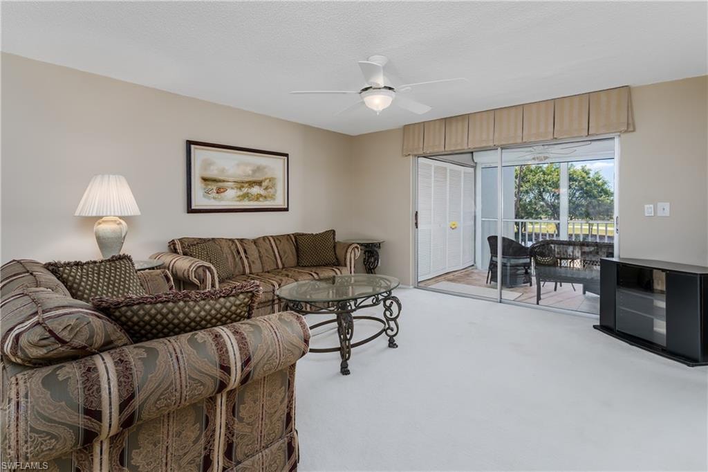 Living area featuring light carpet and ceiling fan